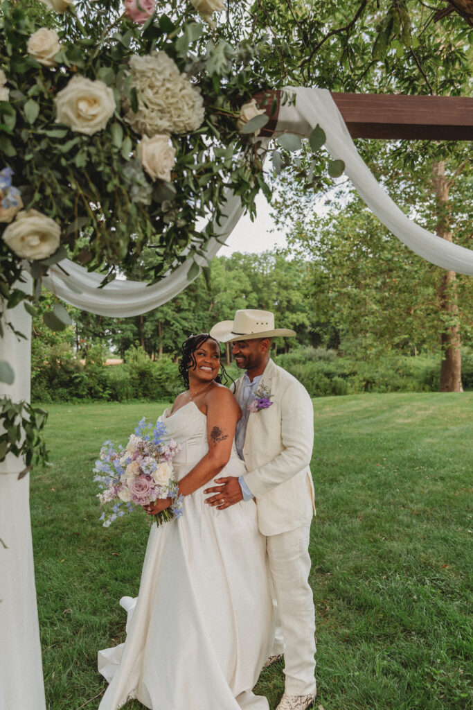 Newlyweds sharing a romantic moment beneath the ceremony arbor