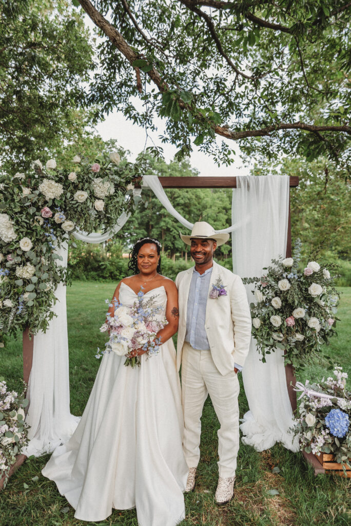 Bride and groom portrait beneath floral wedding arbor at Kennedy Estate