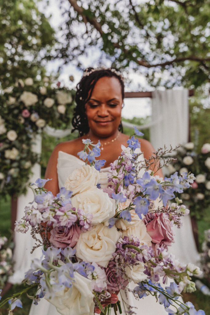 Bride holding purple and blue floral bouquet at Kennedy Estate